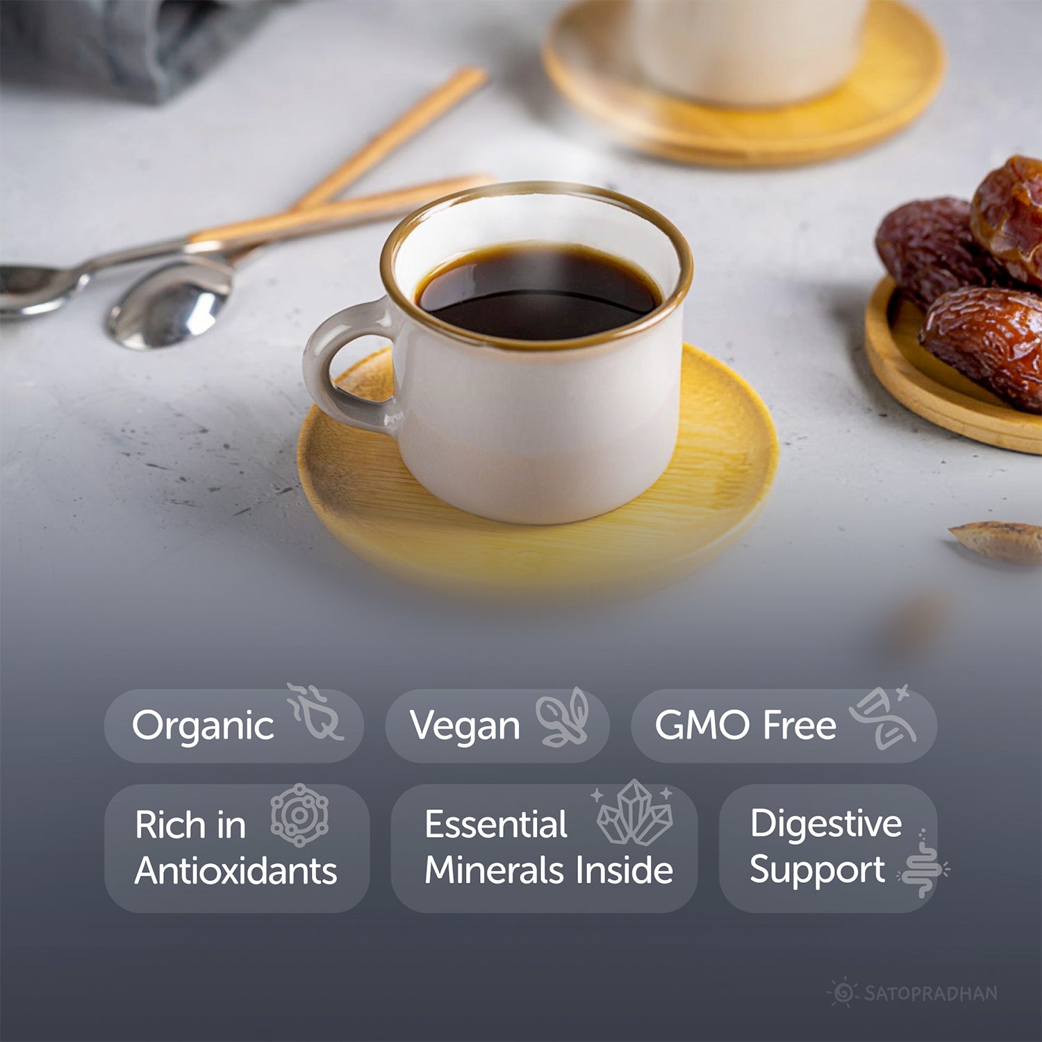 White coffee cup with gold rim on a wooden saucer, surrounded by dates and utensils on a light surface.